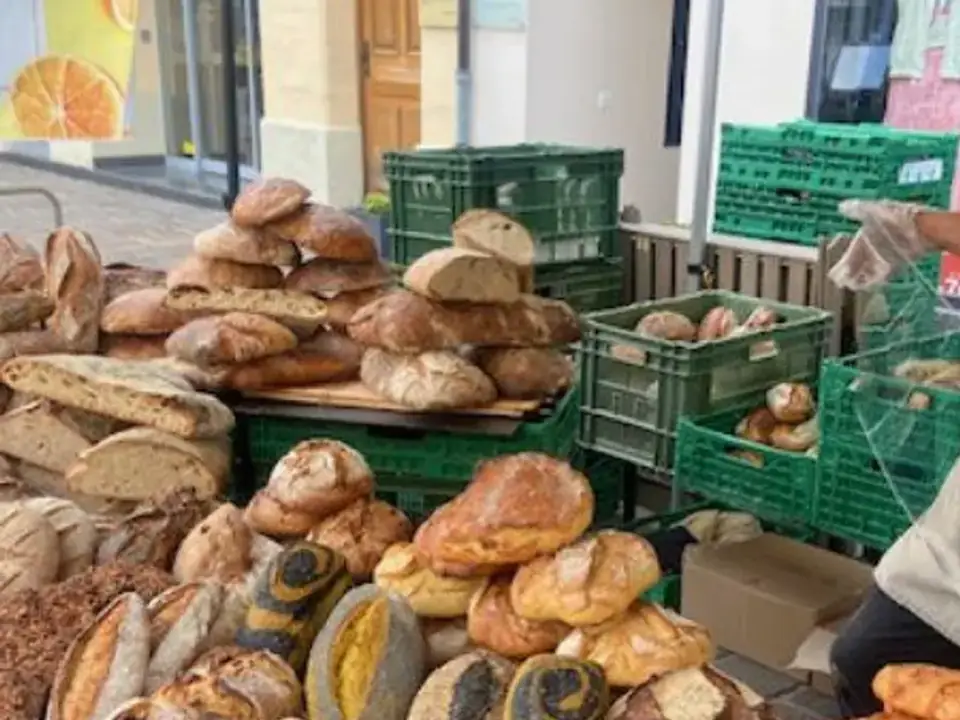 Un étal de pains du marché, miches et couronnes en caisses.